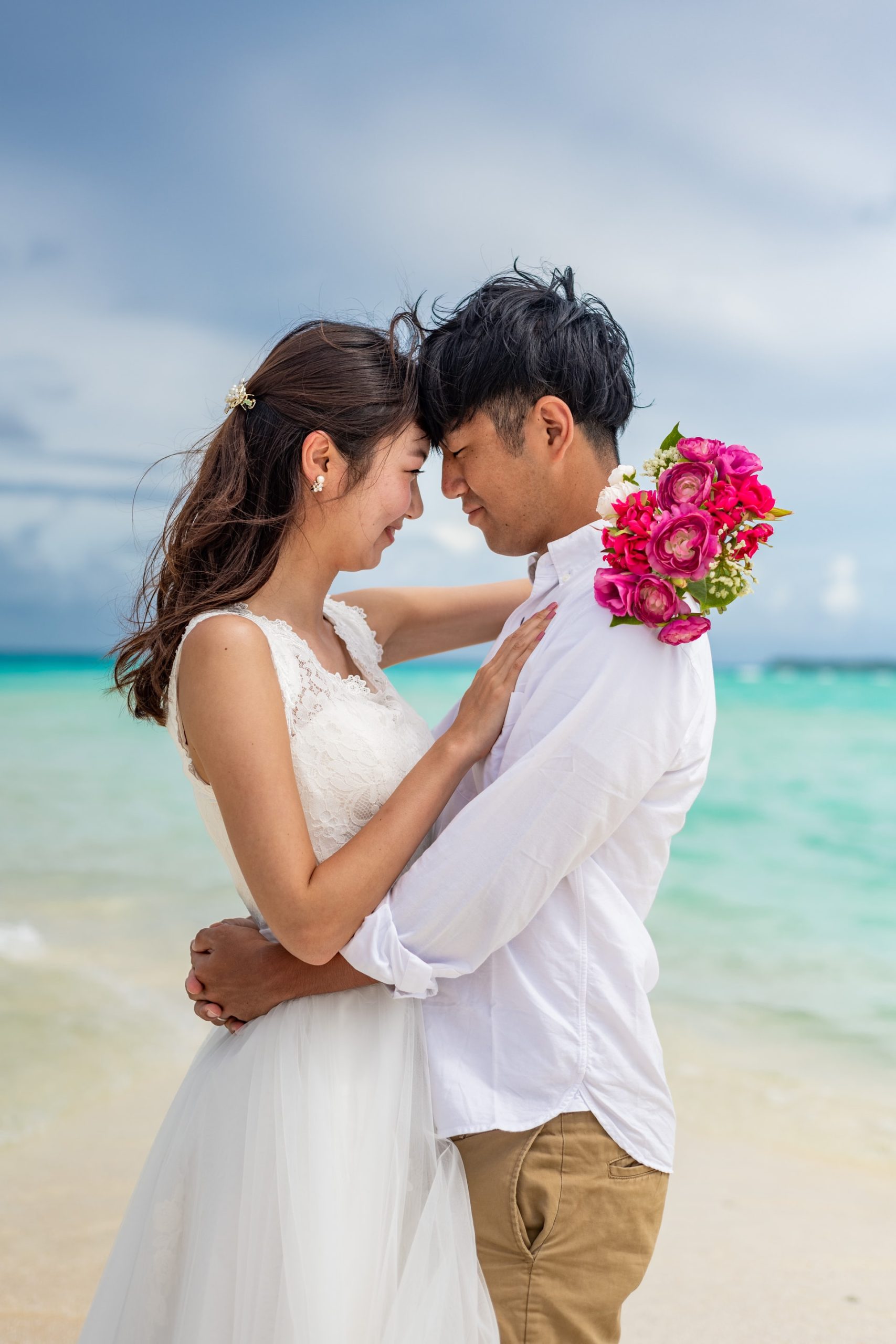 Bride and groom in a loving embrace on the beach.