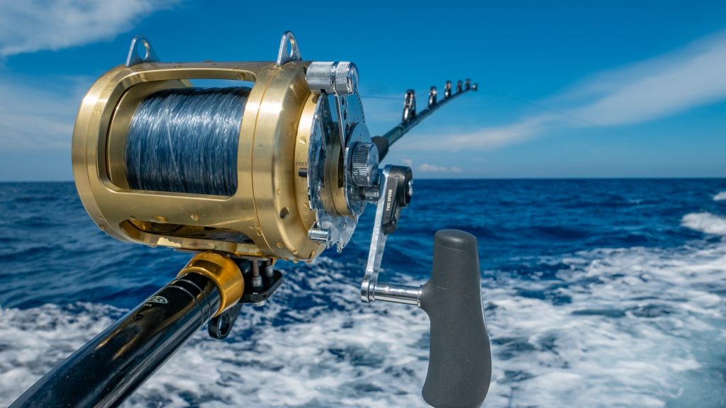 A deep sea fishing rod against the background of a frothy sea and blue sky.