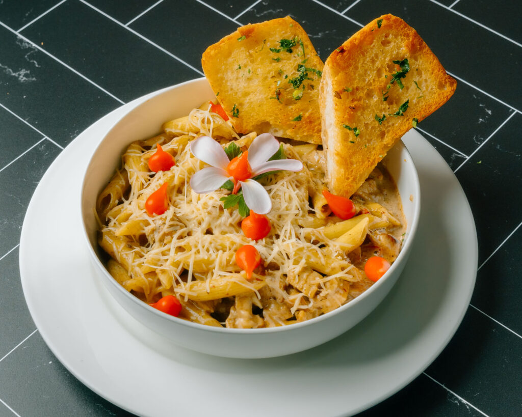 Bistro Pasta - Penne pasta, jerk chicken in a bell pepper & onion creamy curry sauce. Served with garlic naan bread