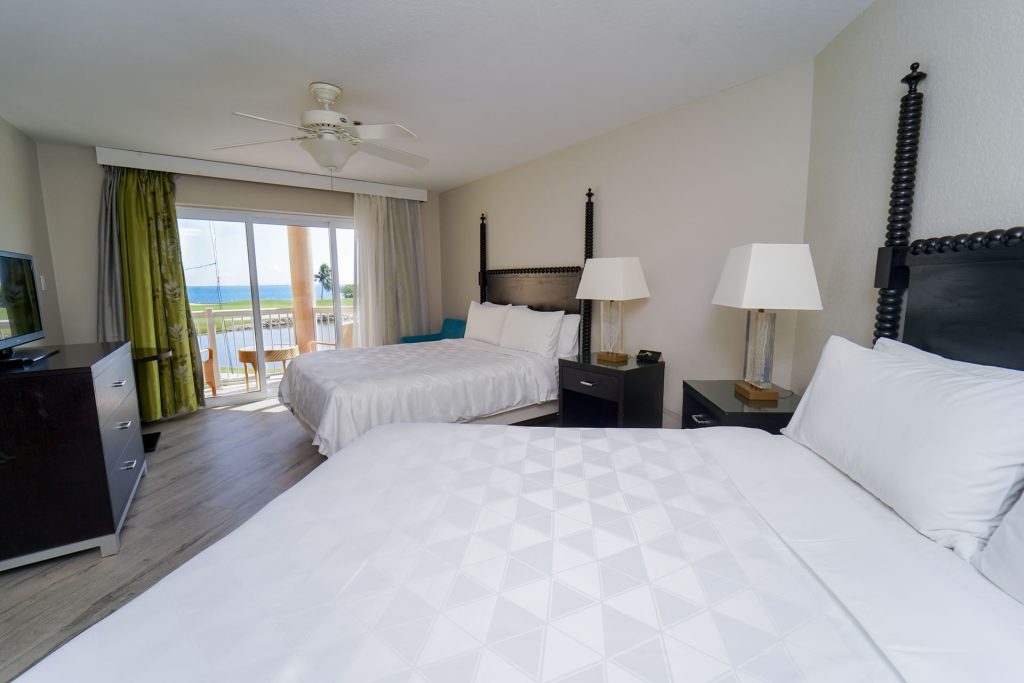 Two queen beds and sunny balcony in the Two Queen Bed Studio Suite at the Grand Caymanian Resort.