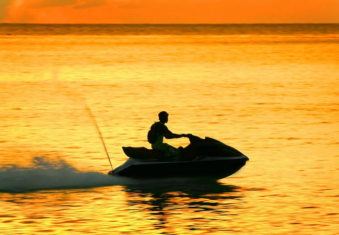 Person on a personal watercraft at sunset.