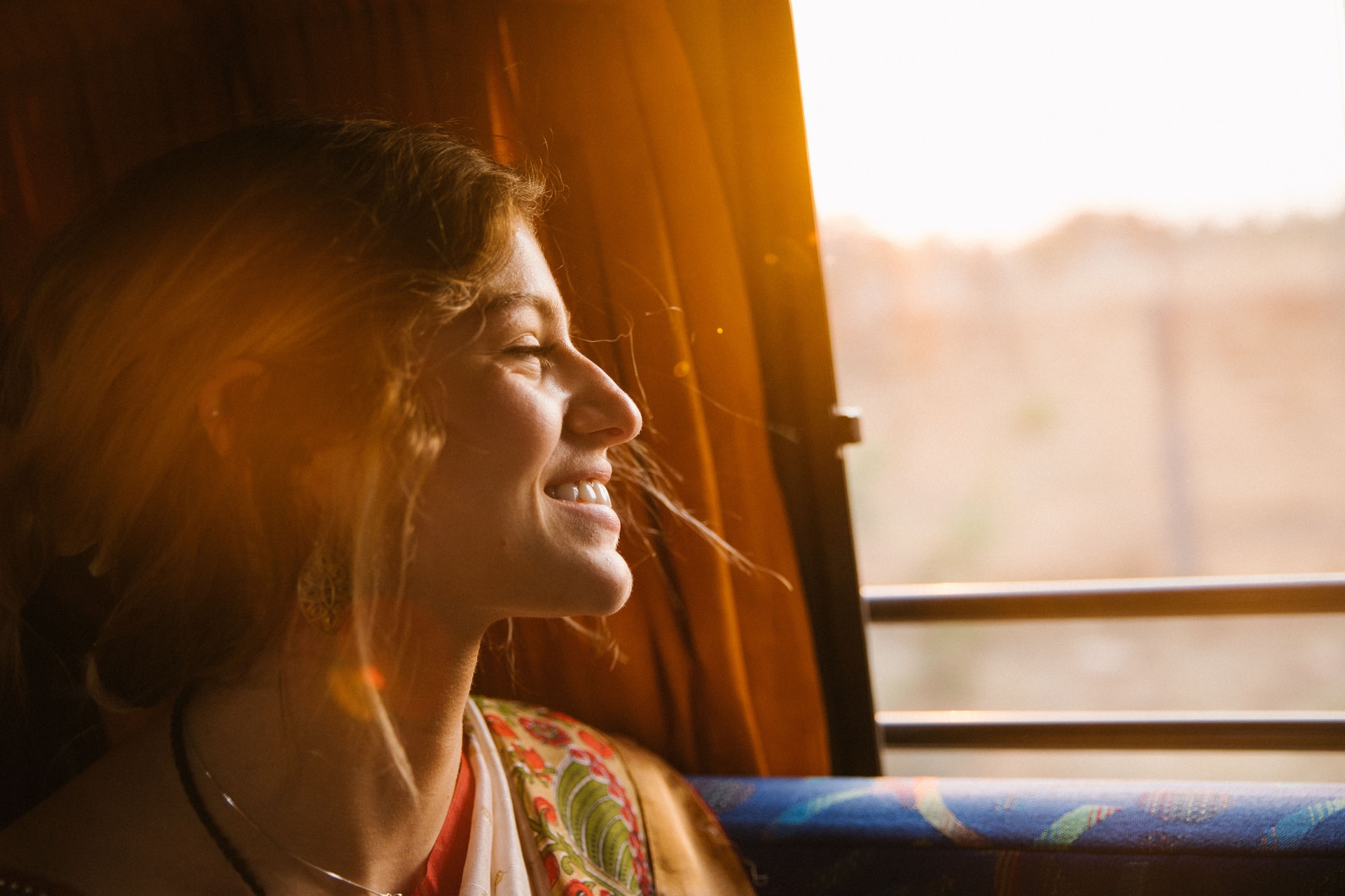 A woman smiling and looking out the window of a shuttle bus.